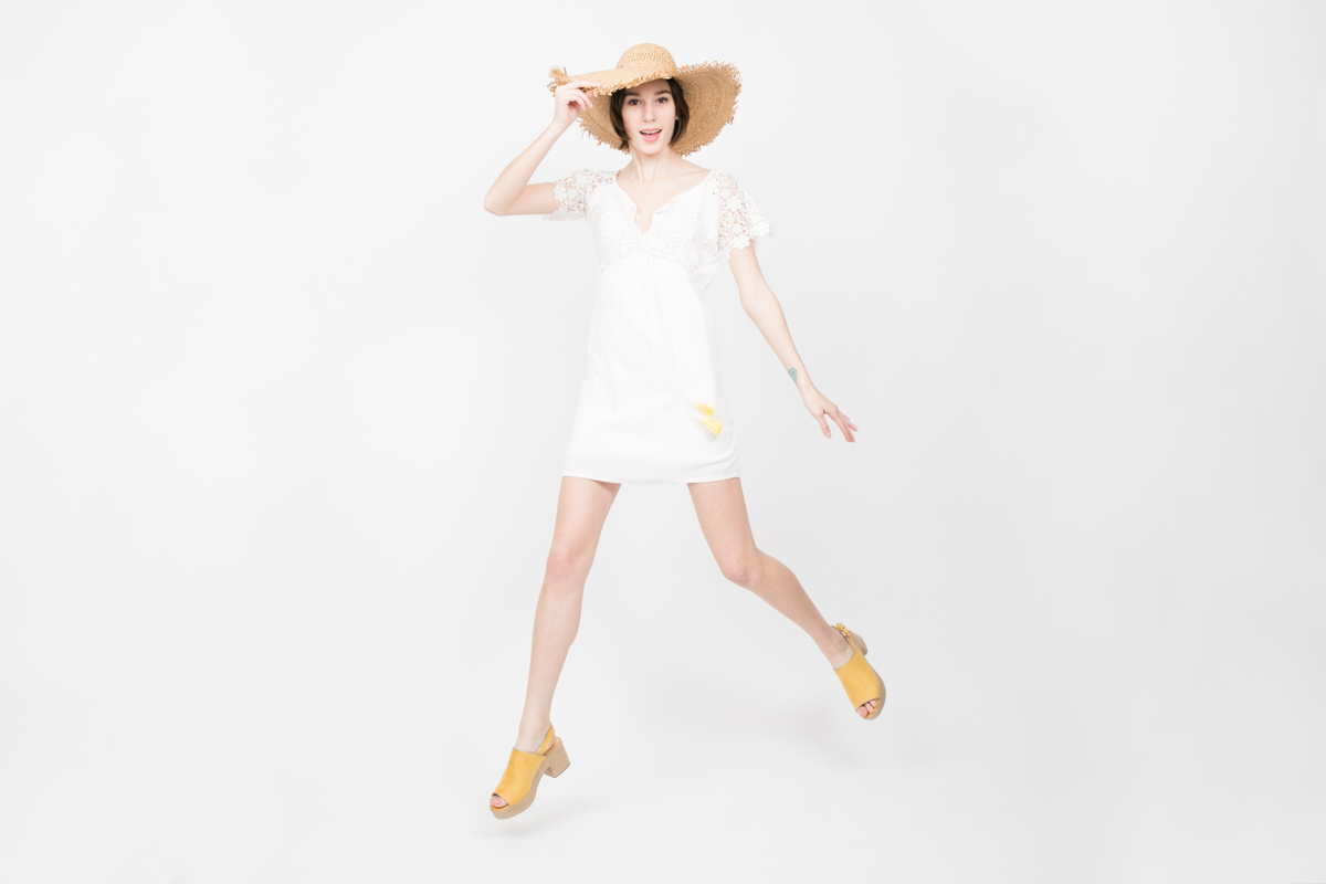 Studio Catalog Shoot for NYC Fashion Retailer Apparis Fashion Photography New York French Designer Clothes Cute Model in Straw Hat and Dress Jumps into Air